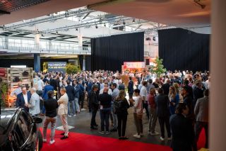 Menschenmenge an einem Wirtschaftsforum in einer grossen Eventhalle, während sich die Teilnehmenden im Networking-Bereich austauschen.